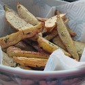 A close up photo of a bowl of roasted fingerling potatoes with rosemary.