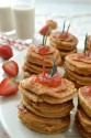Several stacks of pancakes all topped with strawberries.