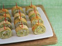 Several wrap bites stabbed with toothpicks on a white appetizer tray.