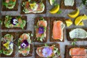 Overhead view of many smoked salmons on a serving tray with various toppings.