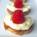 A close up of a row of raspberry topped pastries.