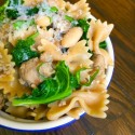 A cup of butterfly pasta on a wooden table.